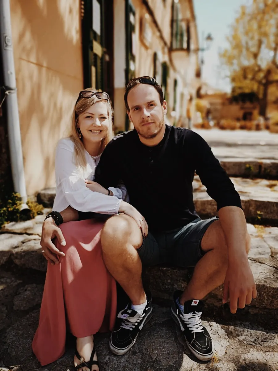 Bente und Philipp sitzen auf einer Treppe vor einer Hauswand