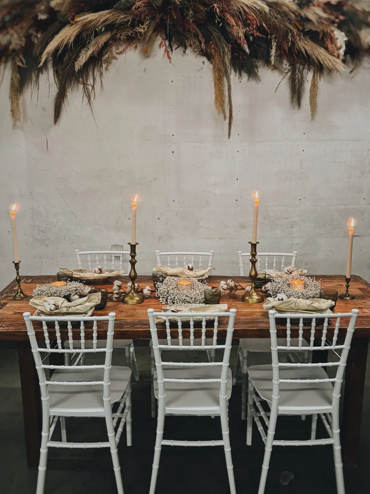 Chiavaristühle mieten Weiße Chiavaristühle an einer Tafel mit Messingkerzenständern und Pampasgras