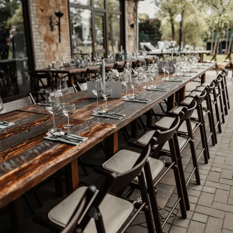 Lange Holztafel mit Metallstühlen in einem Innenhof
