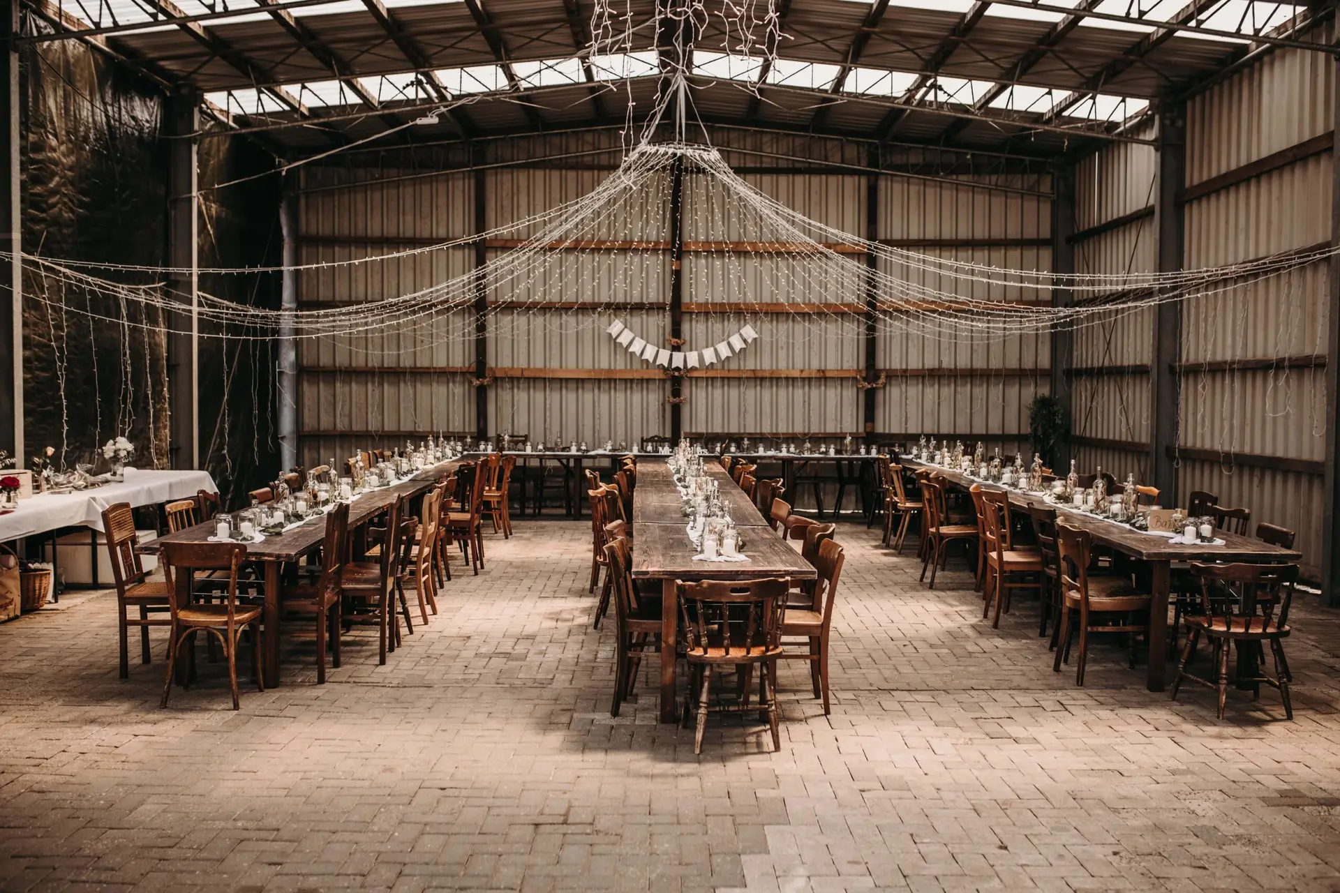 Industriehochzeit Industriehalle mit Holztafeln, Holzstühlen und Lichterketten