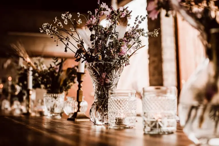 Glasset mit Blumen Glasset mit Wiesenblumen und Kerzen bei Abendlicht