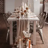 Silberne Metallstühle an einem weißen Holztisch mit Stoffläufer und Kerzen