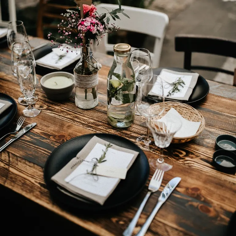 Plankentisch dunkel mieten Dunkler Plankentisch mit schwarzen Tellern, Leinenservietten und Wildblumen