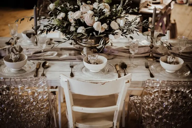 Plankentisch weiß gedeckt Weißer Plankentisch mit Blumen und Goldbesteck
