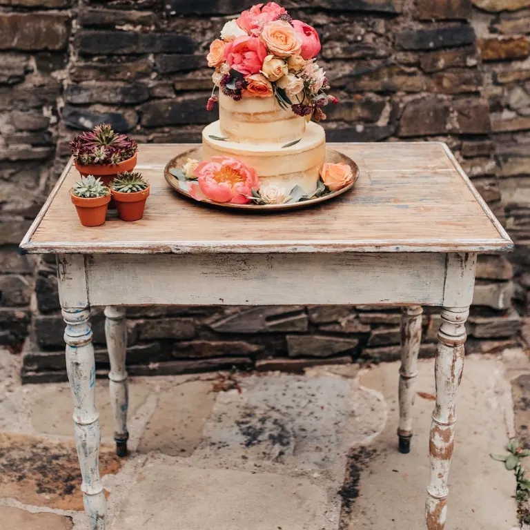 Trautisch weiß mieten Weißer Vintage Trautisch mit dreistöckiger Torte und Sukkulenten vor Backstein