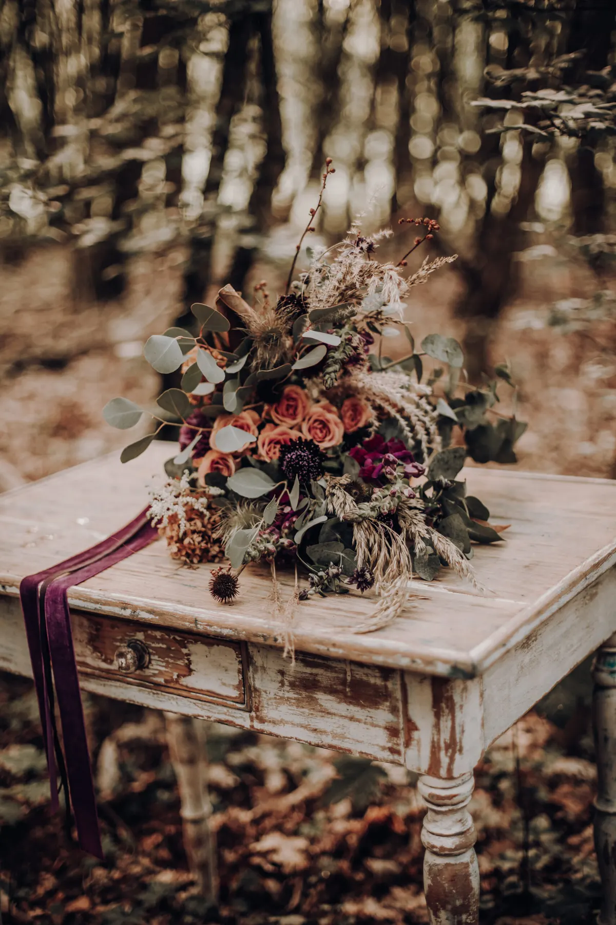Trautisch mit Brautstrauß Brautstrauß auf einem weißen Vintagetisch im Herbstwald